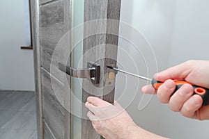 handyman repairing door lock in room, closeup. a repairman repairs the wooden interior door. handyman service