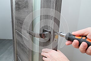 handyman repairing door lock in room, closeup. a repairman repairs the wooden interior door. handyman service