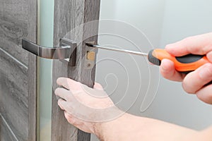 handyman repairing door lock in room, closeup. a repairman repairs the wooden interior door. handyman service