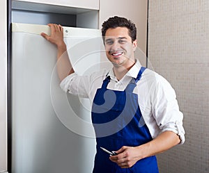 Handyman repairing refrigerator in kitchen