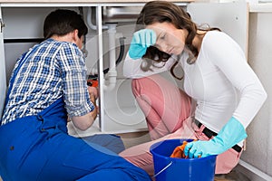 Handyman Repairing Sink Pipe While Woman Squeezing Cloth