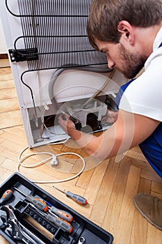Handyman repairs the fridge