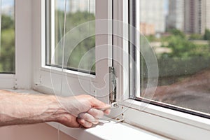 Handyman repairs plastic window with a hexagon. Workman adjusts the operation of the plastic window