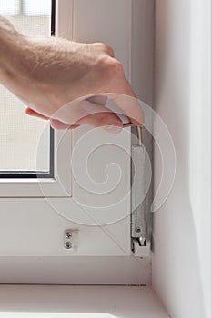 Handyman repairs plastic window with a hexagon. Workman adjusts the operation of the plastic window