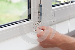 Handyman repairs plastic window with a hexagon. Workman adjusts the operation of the plastic window