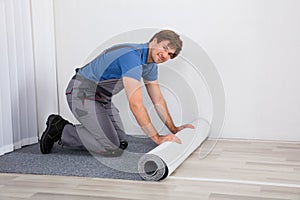 Handyman Rolling Carpet On Floor photo