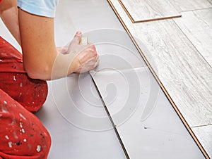 Handyman`s hands laying down laminate flooring boards