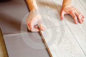 Handyman`s hands laying down laminate flooring boards
