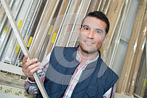 Handyman selecting timber from rack in hardware