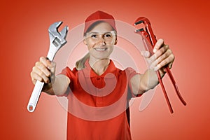 Handyman services - handy woman in red uniform with repair tools in hands on red background