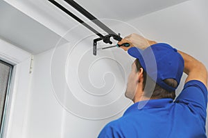 Handyman services - worker installing window curtain rod on the wall