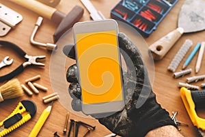 Handyman smart phone app, repairman holding mobile phone in hand