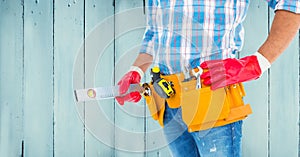 Handyman with tool belt and sprit level against wooden background