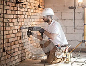 Handyman uses jackhammer, for installation, professional worker on the construction site. The concept of electrician and handyman