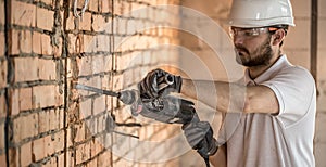 Handyman uses jackhammer, for installation, professional worker on the construction site. The concept of electrician and handyman