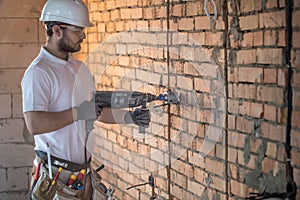 Handyman uses jackhammer, for installation, professional worker on the construction site. The concept of electrician and handyman