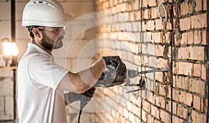 Handyman uses jackhammer, for installation, professional worker on the construction site. The concept of electrician and handyman