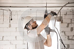 Handyman uses jackhammer, for installation, professional worker on the construction site. The concept of electrician and handyman