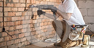 Handyman uses jackhammer, for installation, professional worker on the construction site. The concept of electrician and handyman