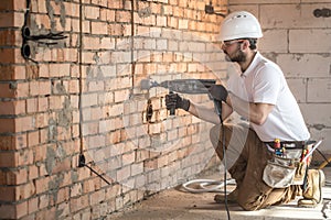 Handyman uses jackhammer, for installation, professional worker on the construction site. The concept of electrician and handyman