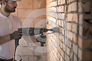 Handyman uses jackhammer, for installation, professional worker on the construction site. The concept of electrician and handyman