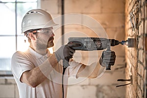 Handyman uses jackhammer, for installation, professional worker on the construction site. The concept of electrician and handyman