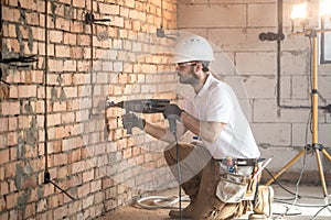 Handyman uses jackhammer, for installation, professional worker on the construction site. The concept of electrician and handyman