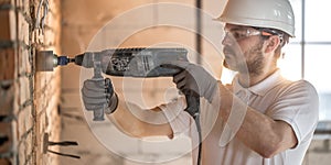 Handyman uses jackhammer, for installation, professional worker on the construction site. The concept of electrician and handyman