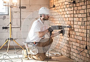 Handyman uses jackhammer, for installation, professional worker on the construction site. The concept of electrician and handyman