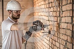 Handyman uses jackhammer, for installation, professional worker on the construction site. The concept of electrician and handyman