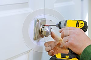 Handyman using a drill to installing lock in door in a house