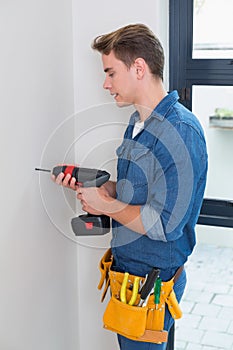 Handyman using a drill with toolbelt around waist