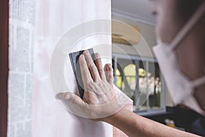 A handyman using a piece of sandpaper to smoothen out the side of a wall cabinet prior to painting. Home renovation or finishing photo