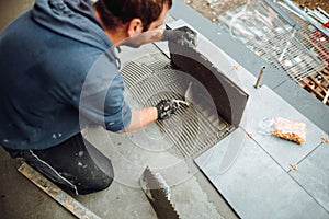 a handyman using a tile spacer to adjust the tile level. Repair work, construction details