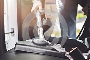 Handyman vacuuming car back seat with vacuum cleaner