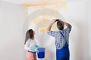 Handyman With Woman Photographing Ceiling At Home