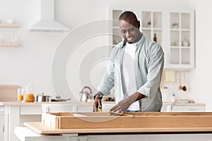 Handyman working at home, repairing, assembling and renovation or new hobby. Man measuring new table with tape-line