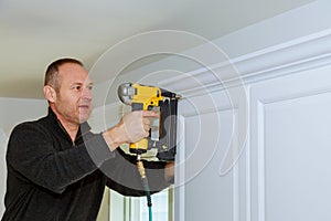 Handyman working instal brad nail gun to Crown Moulding wall cabinets framing trim