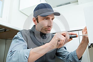 Handyman working in kitchen using screwdriver