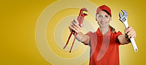 Handywoman in red uniform with tools in hands on yellow background with copy space