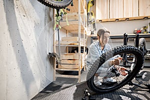 Handywoman reparing bicycle in the workshop