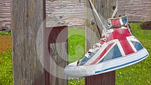 hang british flag sneakers shoes to fence - hipster shoes reuse in natural background