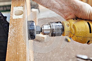 Hang a door, carpenter drillings lock latch hole, close-up.