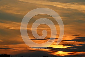 Hang glider in colored sunset sky