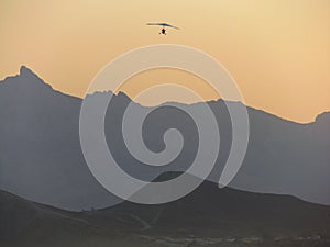 A hang-glider flying over the mountains