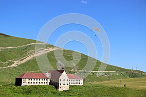 hang glider and a house with a red roof in the mountains