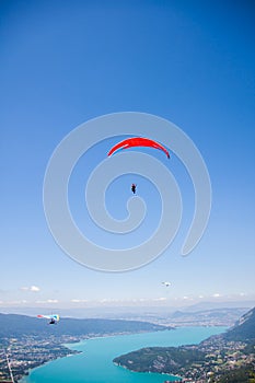 Hang-glider and Paraglider Flying over Annecy Lake Through Mountain Landscape and Cities