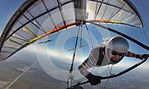 Hang glider pilot on colorful wing flies together with eagle