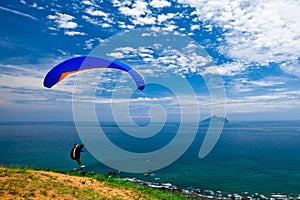Hang glider in sky over blue sea