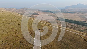 Hang gliders take off from the runway in the mountains above the valley with a dried lake and vineyards